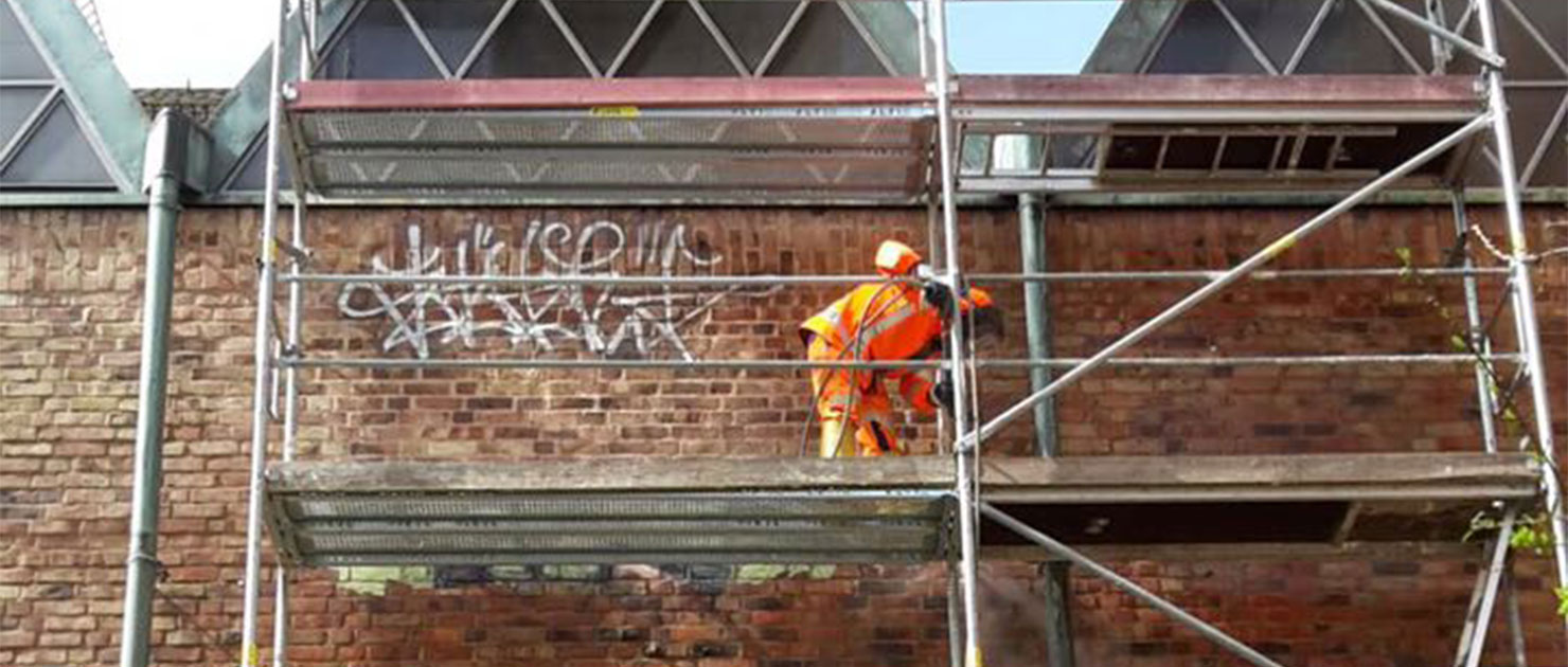 FFR-Mitarbeiter auf einem Gerüst entfernt Graffiti