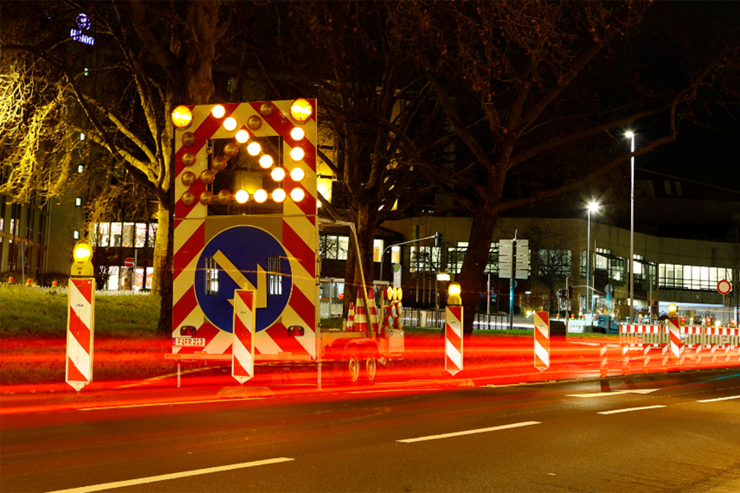 Leuchtende Leitbaken und Warnschilder einer Straßenabsperrung bei Nacht
