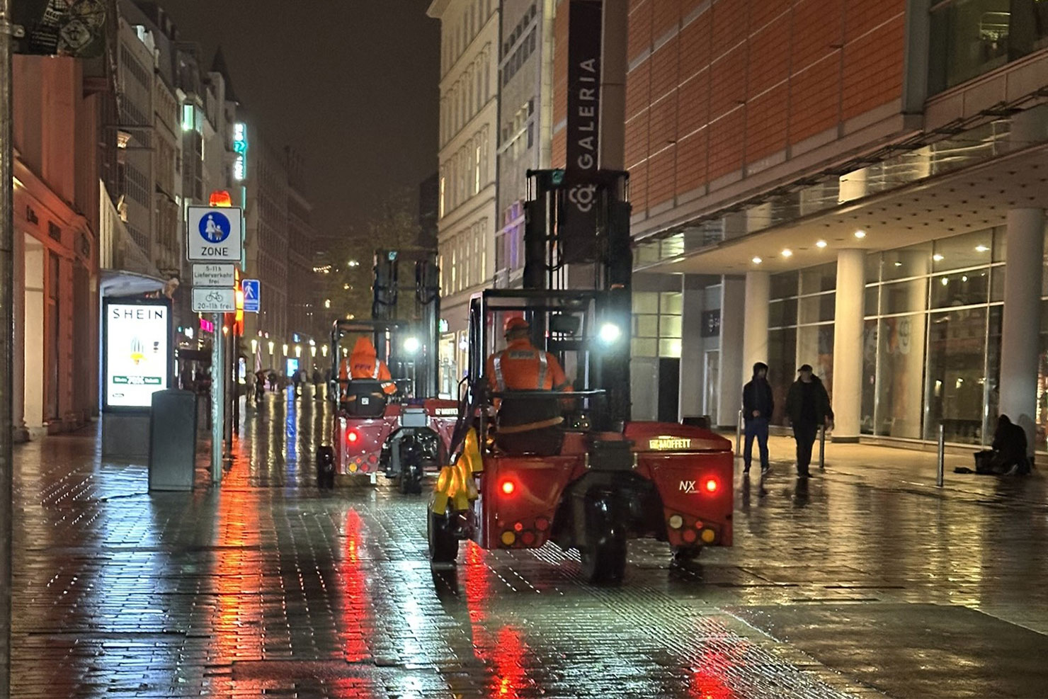 Transportfahrzeuge für mobile Fahrzeugsperren fahren bei Nacht durch eine Fußgängerzone