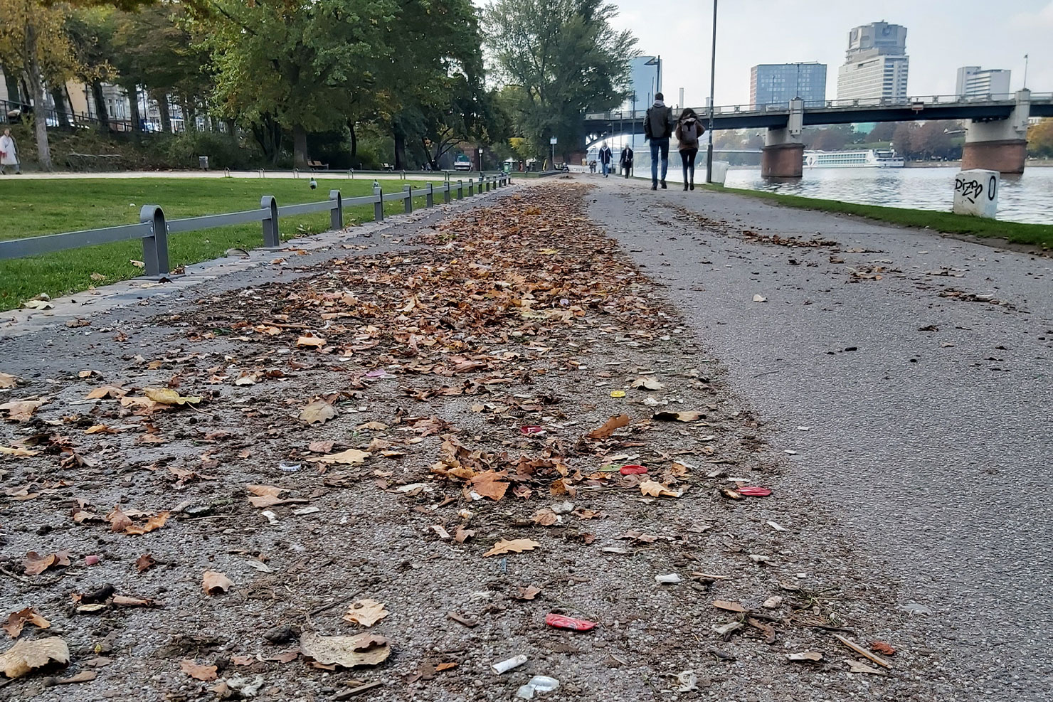 Mit Müll bedeckter Gehweg an Flussufer