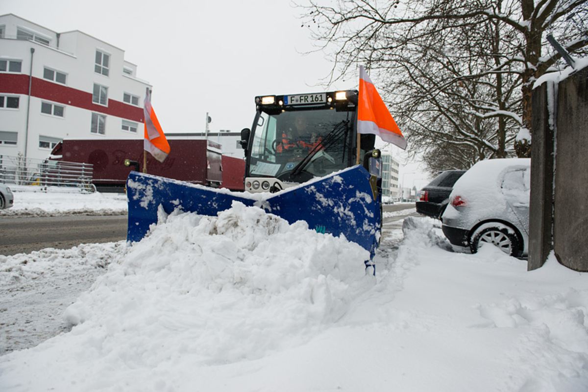 Kleines Großräumfahrzeug räumt Schnee auf einer Straße