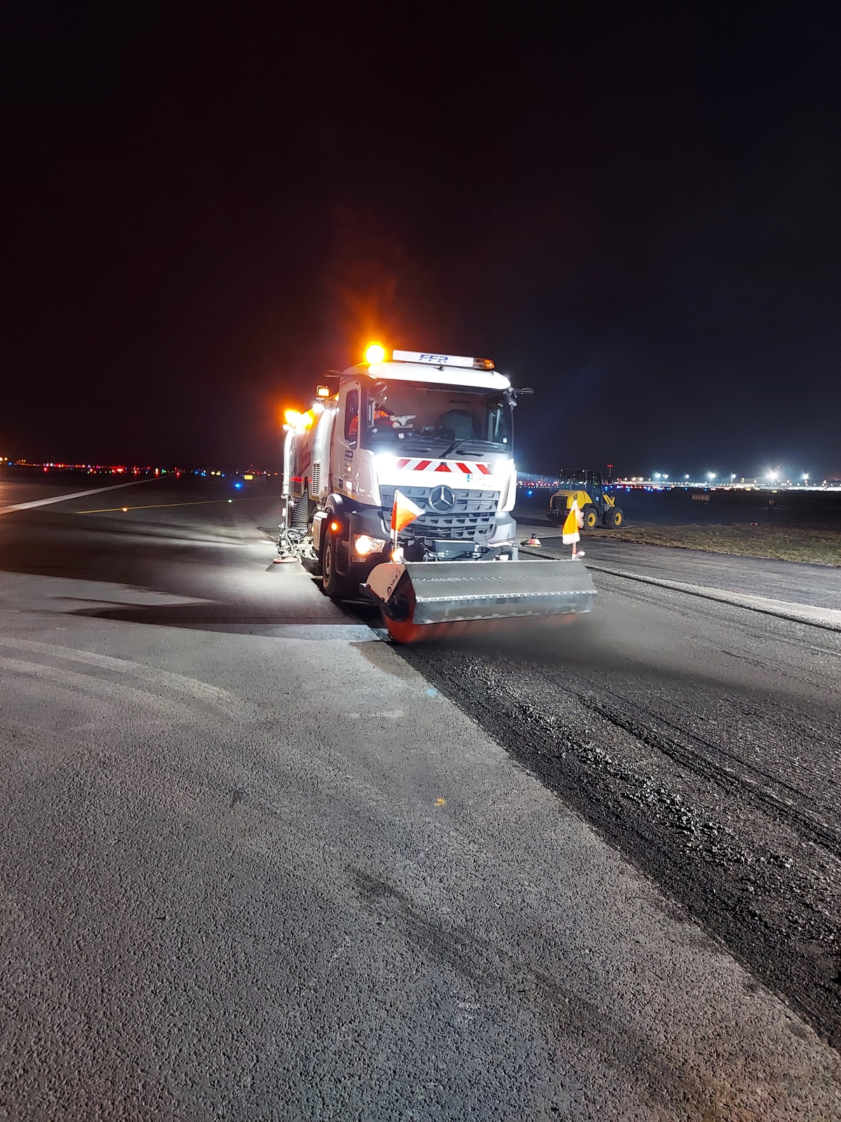 Eine Großkehrmaschine reinigt eine Straße bei Nacht