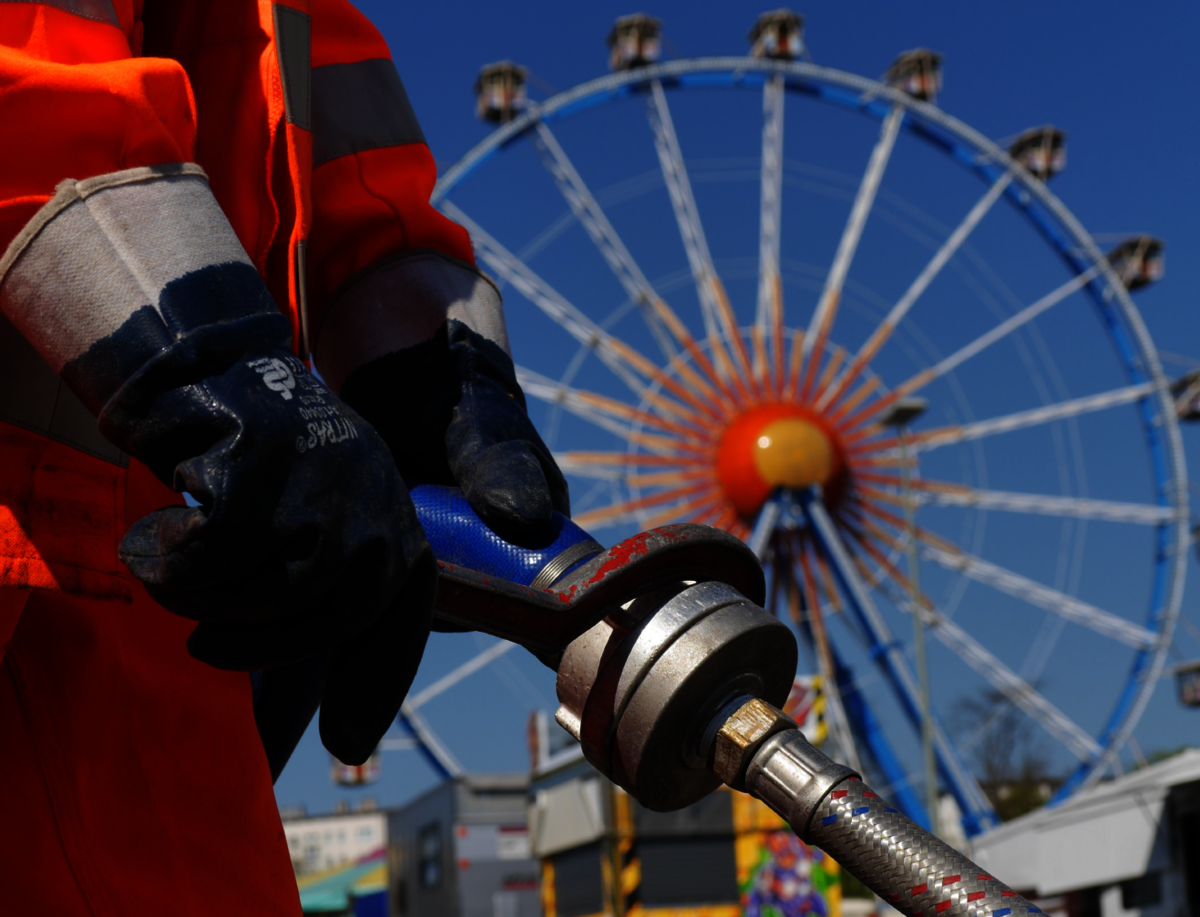 Mitarbeiter arbeitet an mobiler Wasserversorgung, im Hintergrund Riesenrad