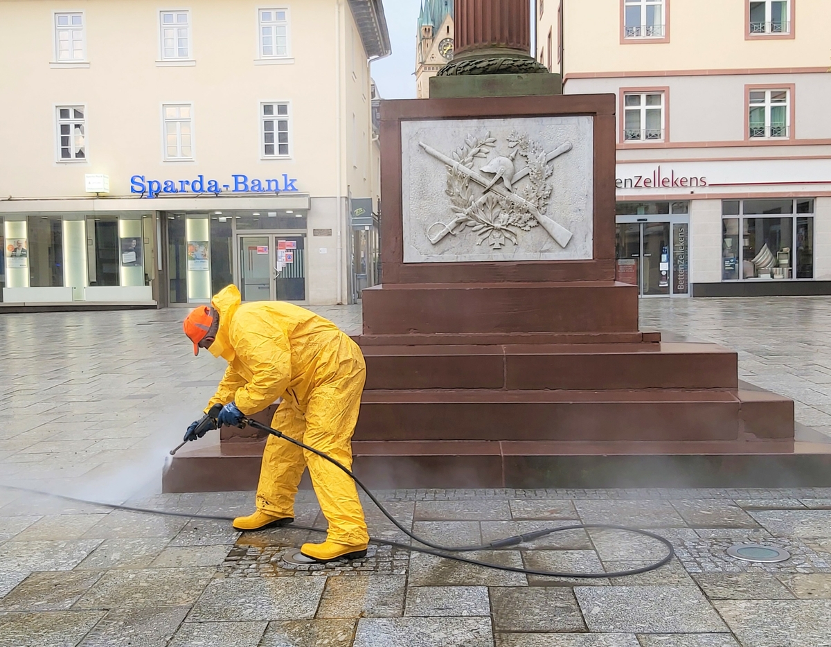 Mitarbeiter in Schutzkleidung reinigt Treppenstufen mit einem Hochdruckreiniger