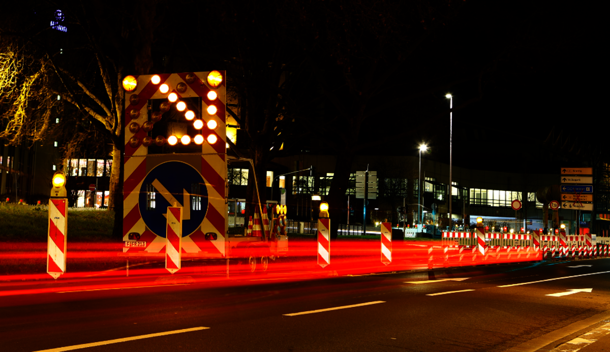 Leuchtende Leitbaken und Warnschilder einer Straßenabsperrung bei Nacht