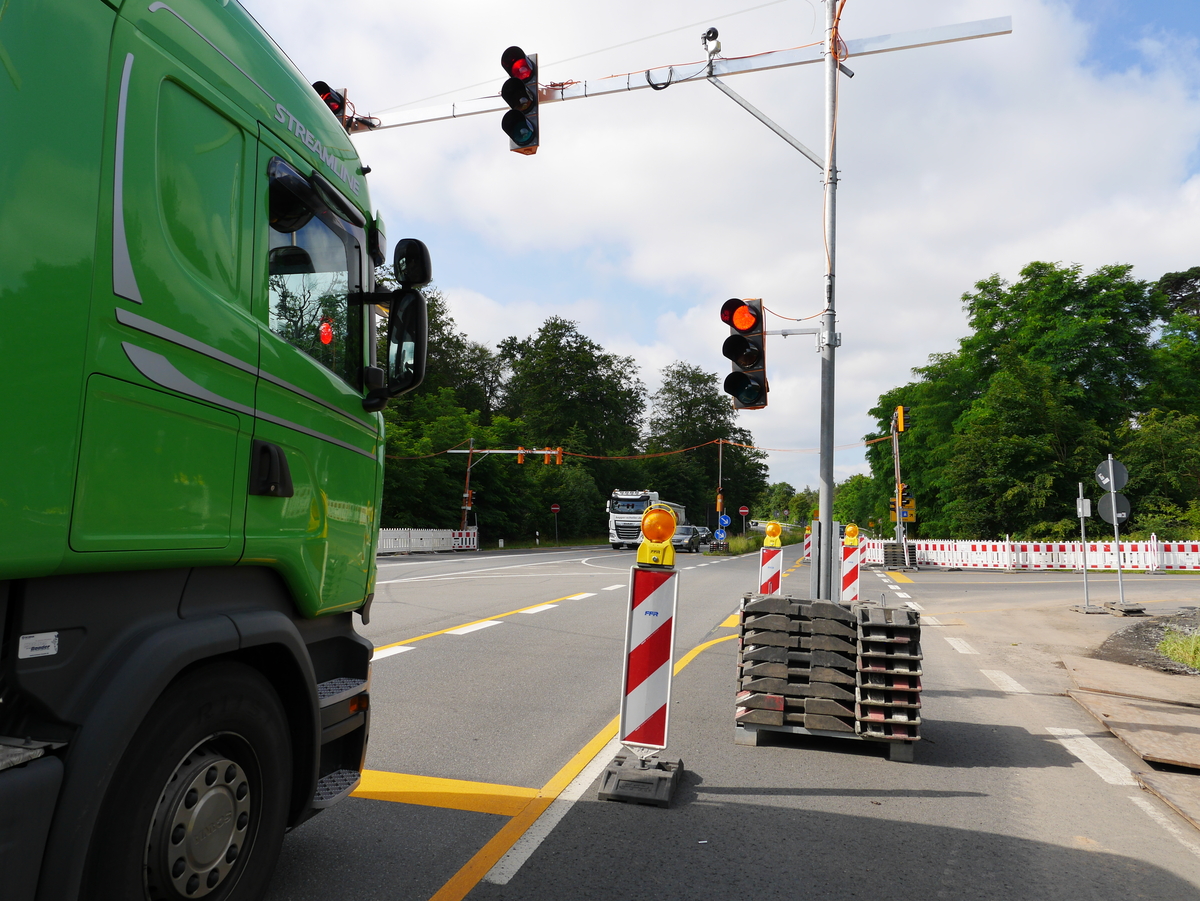 Fahrzeug steht an mobiler Ampel und Absperrungen an einer Straße